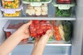 Woman taking plastic bag with tomatoes from refrigerator, closeup