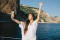 Woman taking selfie on smart phone on yacht.