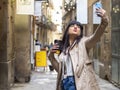 Woman taking a selfie on the street kissing the cellphone camera and holding a disposable coffee