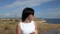 Woman Taking a Sip of Coffee by Sea in the background lighthouse