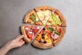 Woman taking slice of delicious pizza at grey table Royalty Free Stock Photo