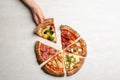 Woman taking slice of delicious pizza at grey table, top view Royalty Free Stock Photo