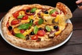 Woman taking slice of tasty vegetable pizza at wooden table Royalty Free Stock Photo