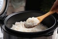 Woman taking tasty rice with spoon from cooker in kitchen Royalty Free Stock Photo