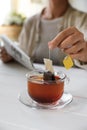 Woman taking tea bag out of cup at white wooden table indoors, closeup Royalty Free Stock Photo