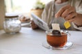 Woman taking tea bag out of cup at white wooden table indoors, closeup. Space for text Royalty Free Stock Photo