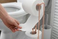 Woman taking toilet paper from roll holder in bathroom Royalty Free Stock Photo