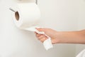 Woman taking toilet paper from roll holder on white wall Royalty Free Stock Photo