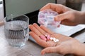 Woman taking Daily vitamins white working on laptop Organizer weekly shots Closeup of medical pill box with doses of