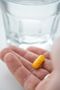 Woman taking yellow pill tablet medicine with glass of water