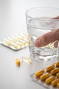 Woman taking yellow pills tablets medicine of blister with glass of water Royalty Free Stock Photo