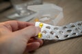 Woman taking yellow pills tablets medicine of blister and pillbox with glass of water on wooden nightstand table Royalty Free Stock Photo