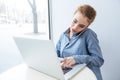 Woman talking on cell phone and using laptop in cafe Royalty Free Stock Photo