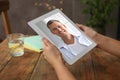 Woman talking with handsome man using video chat on tablet at wooden table, closeup. Online dating Royalty Free Stock Photo