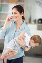 woman talking on mobile phone while carrying daughter Royalty Free Stock Photo