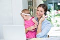 Woman talking on mobile phone while sitting with baby girl Royalty Free Stock Photo