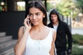 Woman talking on mobile phone and stalked by man criminal Royalty Free Stock Photo