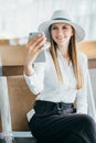 Woman talking on the phone at the airport terminal. Portarit of a young female traveler with a luggage and coffee cup Royalty Free Stock Photo