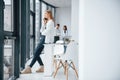 Woman talking by phone in front of group of young successful team that working and communicating together indoors in Royalty Free Stock Photo