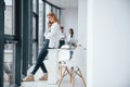 Woman talking by phone in front of group of young successful team that working and communicating together indoors in Royalty Free Stock Photo