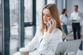 Woman talking by phone in front of group of young successful team that working and communicating together indoors in Royalty Free Stock Photo