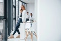 Woman talking by phone in front of group of young successful team that working and communicating together indoors in Royalty Free Stock Photo