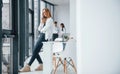 Woman talking by phone in front of group of young successful team that working and communicating together indoors in Royalty Free Stock Photo