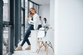 Woman talking by phone in front of group of young successful team that working and communicating together indoors in Royalty Free Stock Photo