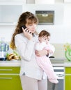 Woman talking on the phone while holding her baby in her arms Royalty Free Stock Photo