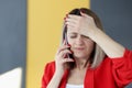 Woman is talking on phone and holding her forehead with her hand Royalty Free Stock Photo