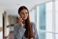 A woman talking on the phone in the office of a building and looking out the window at the big city. High quality photo Royalty Free Stock Photo