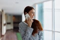 A woman talking on the phone in the office of a building and looking out the window at the big city. High quality photo Royalty Free Stock Photo