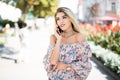 Woman talking by phone outdoors in city street. Portrait of young smiling girl standing with smartphone Royalty Free Stock Photo