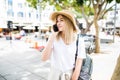 Young woman talking by phone outdoors in city street. Portrait of young smiling fashion girl standing with smartphone Royalty Free Stock Photo