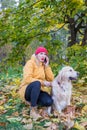 Woman talking on the phone while sitting with a dog under a tree Royalty Free Stock Photo