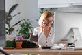 Woman speaking on phone, using calculator to calculate the invoice, working on desktop from home, cat sitting on the table Royalty Free Stock Photo