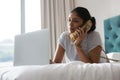 Woman talking on phone while using laptop on bed Royalty Free Stock Photo