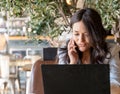 Woman talking on the phone while working with a laptop in a coffee shop Royalty Free Stock Photo