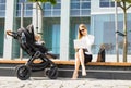 Woman talking on the phone and working on laptop outdors while having a baby in stroller Royalty Free Stock Photo