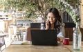 Woman talking on the phone while working online with a laptop computer in a coffee shop Royalty Free Stock Photo