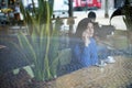 Woman talking on smart phone while sitting in cafe seen through window Royalty Free Stock Photo