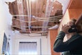 Woman talking to homeowner`s insurer while inspecting kitchen ceiling
