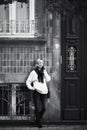 A woman talks on her cell phone while standing in front of a traditional house on a street in Porto, Portugal.