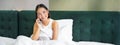 Woman talks on mobile phone in bed. Smiling girl having telephone conversation while relaxing in bedroom Royalty Free Stock Photo