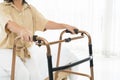 A woman in a tan shirt is using a walker. The walker is made of metal and has a black handle Royalty Free Stock Photo