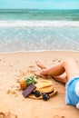 Woman tanned legs on sand beach. Sun glasses, pineapple, hat and passport on the beach and sea water flow Royalty Free Stock Photo