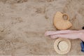 Woman tanned legs, straw hat and bag on sand beach. Travel concept. Relaxing at a beach, with your feet on the sand Royalty Free Stock Photo