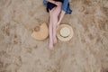 Woman tanned legs, straw hat and bag on sand beach. Travel concept. Relaxing at a beach, with your feet on the sand Royalty Free Stock Photo