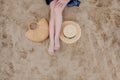 Woman tanned legs, straw hat and bag on sand beach. Travel concept. Relaxing at a beach, with your feet on the sand. Royalty Free Stock Photo