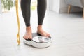 Woman with tape standing on scales indoors, space for text. Overweight